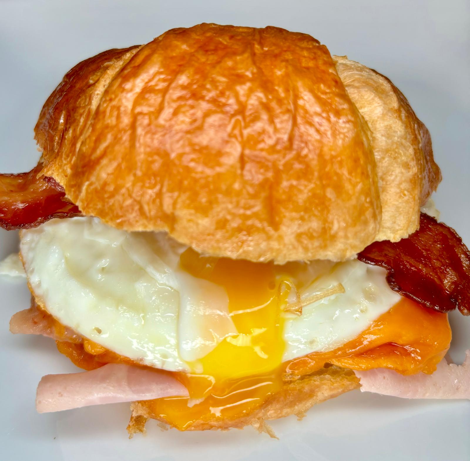 croissant, jamon, queso, huevo y bacon